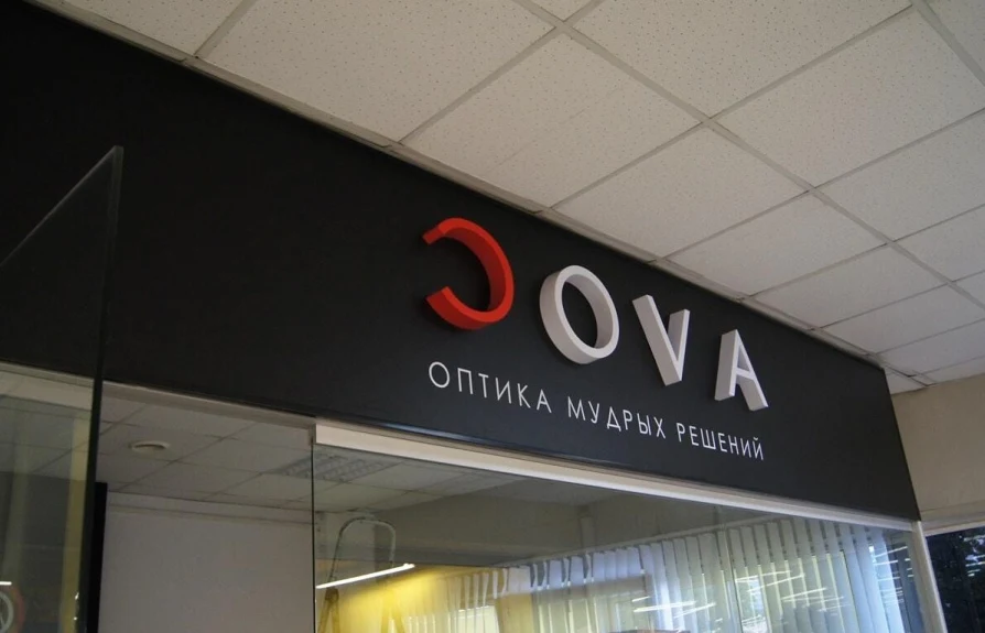 Несветовые объёмные буквы Cova на чёрной панели над входом в оптику