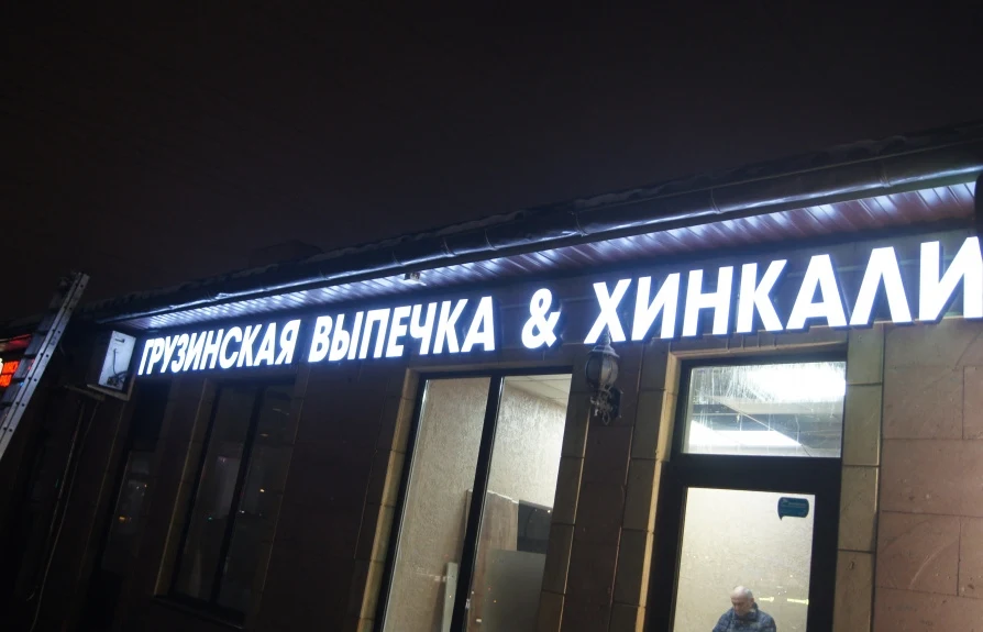 Светящаяся надпись «Грузинская выпечка & хинкали» над окнами, вид снизу