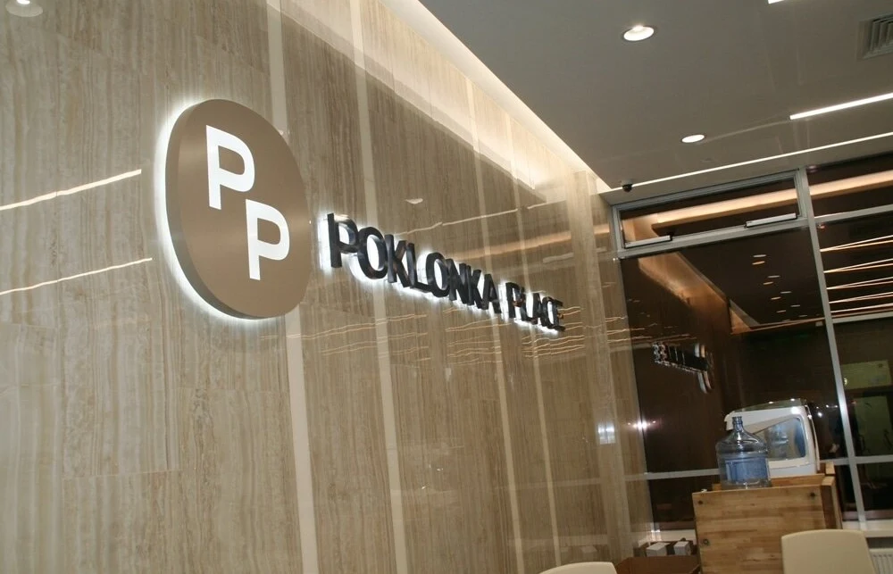 Объёмные буквы Poklonka Place и круглая эмблема PP на фактурной стене