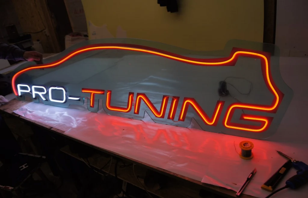 Неоновая вывеска Pro-Tuning с белой надписью PRO и красно-оранжевым автомобильным контуром