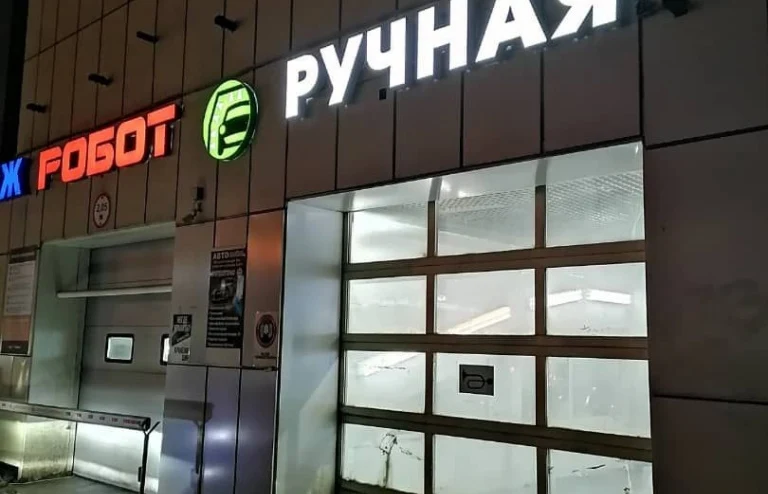 Белые световые буквы «Ручная» на фасаде автомойки рядом с соседними обозначениями