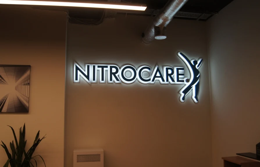 Вывеска Nitrocare с контражуром на стене за ресепшн