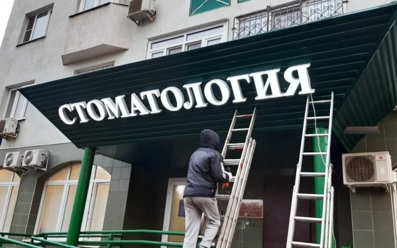 Световая надпись «Стоматология» на зелёном козырьке
