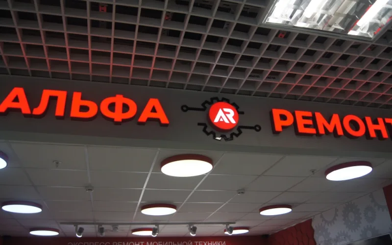 Красные световые буквы «Альфа Ремонт» и круглый логотип на сером фризе Красные световые буквы «Альфа Ремонт» и круглый логотип на сером фризе