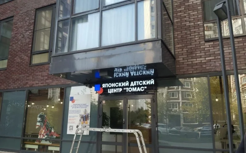 Вывеска «Японский детский центр Томас» под козырьком входа