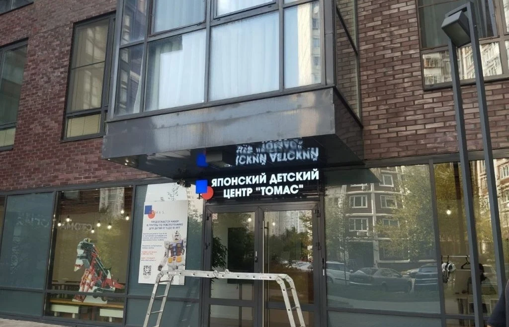 Вывеска «Японский детский центр Томас» под козырьком входа