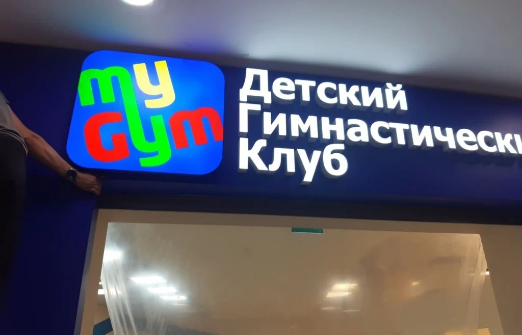 Логотип My Gym и белая световая надпись детского гимнастического клуба