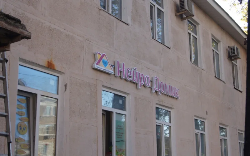 Вывеска «Нейро Домик» с розовыми буквами на светлом фасаде