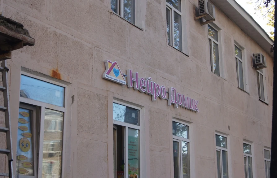 Вывеска «Нейро Домик» с розовыми буквами на светлом фасаде