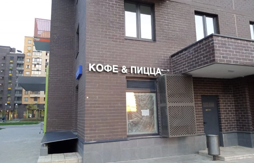 Белая надпись «Кофе & Пицца» на кирпичном фасаде