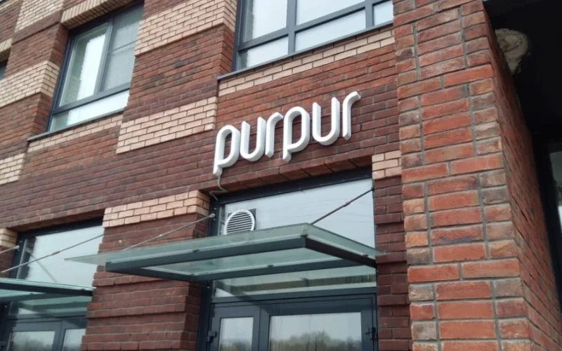 Световая вывеска PurPur на кирпичном фасаде над входом