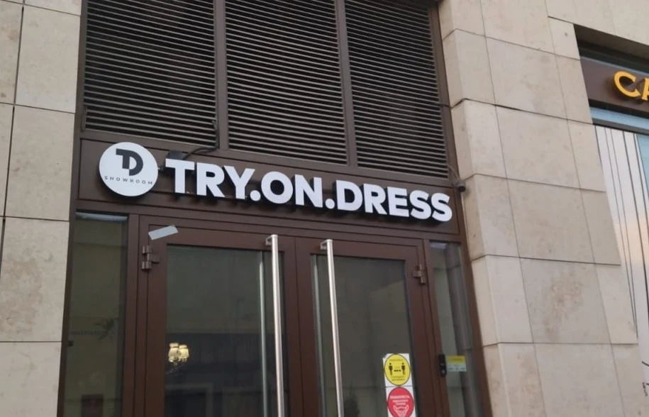 Световая вывеска TRY.ON.DRESS с круглым логотипом над входом