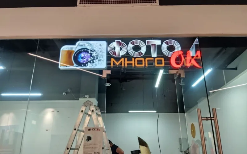 Монтаж световой вывески «Много Фоток» над стеклянной витриной фотосалона