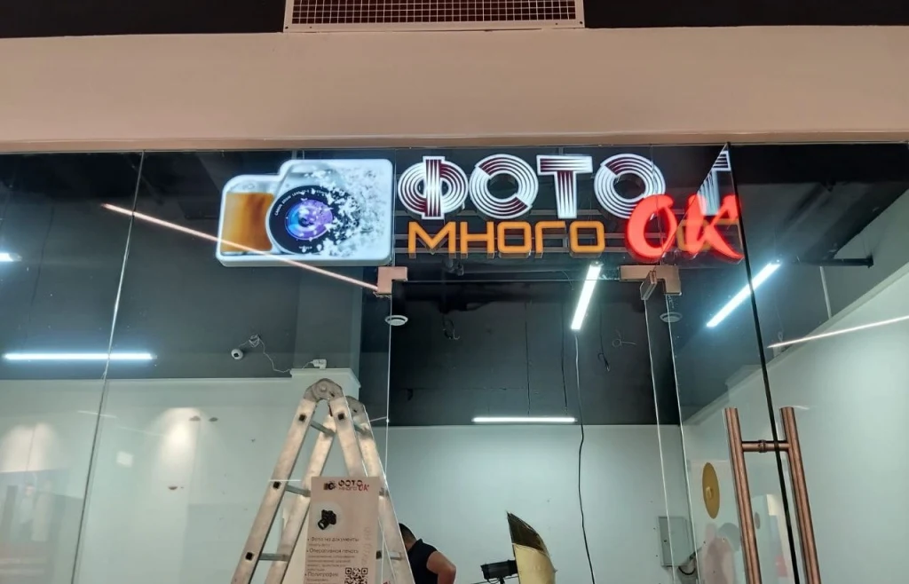 Монтаж световой вывески «Много Фоток» над стеклянной витриной фотосалона